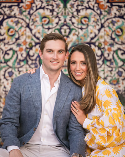 Photo of couple posing in from of decorative wall for engagement