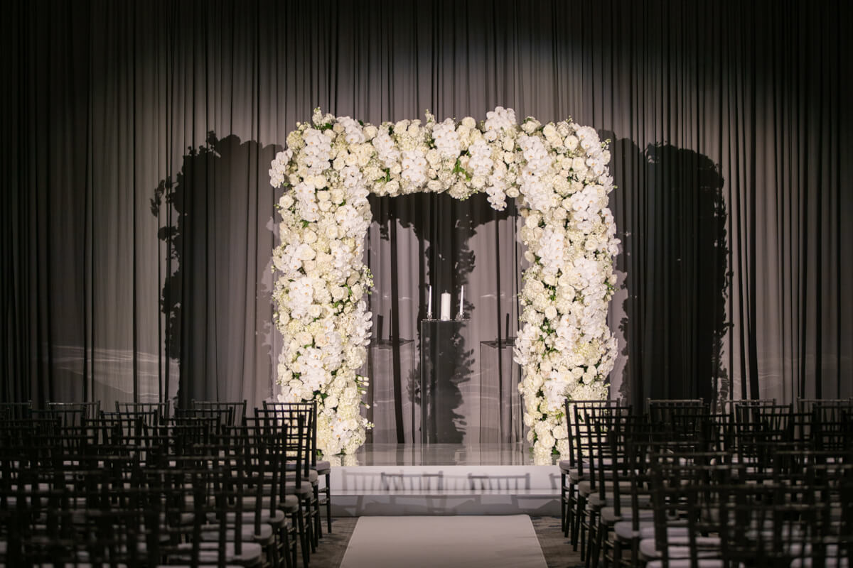 white floral arch in front of silver draping