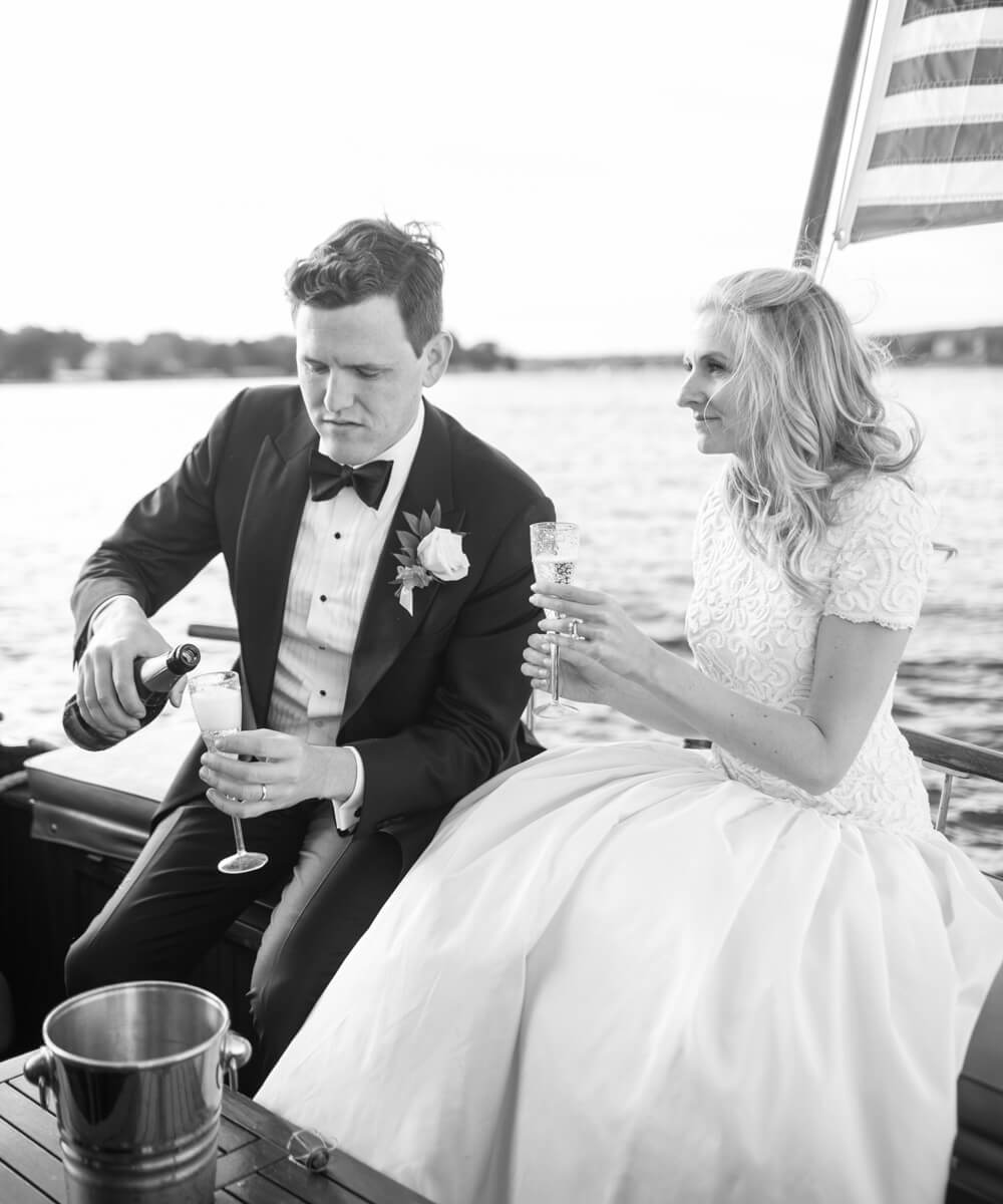 natalie and tom pouring champagne on a boat